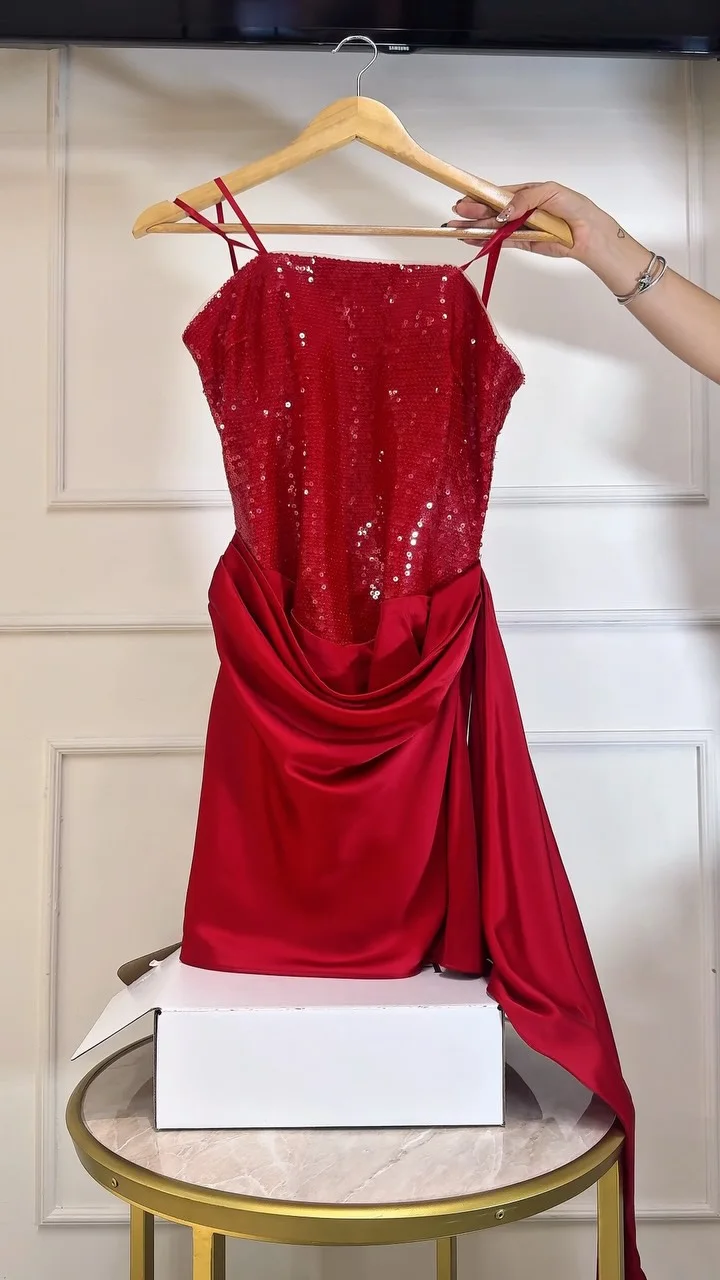 Vestido corto rojo, de lentejuela arriba y satén drapeado abajo, colgado en su gancho